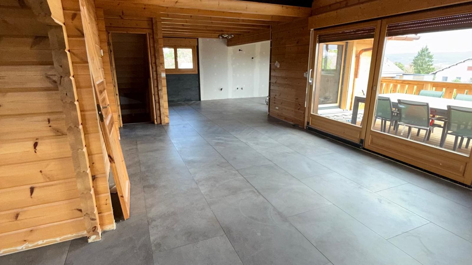 Séjour de chalet avec vue sur la terrasse, carrelage grand format posé par VA Rénovation